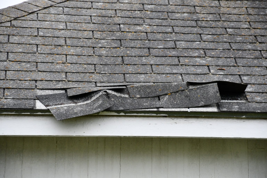 Wind damaged roof shingles on a residential home requiring fixing.